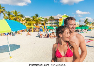 Happy Summer Interracial Couple Portrait On Fort Myers Beach Travel Holiday, Florida, USA. Asian Bikini Woman With Caucasian Man Smiling Relaxing Sunbathing On Holidays.