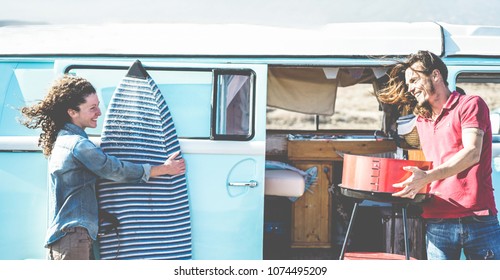 Happy surfer couple camping in road trip vacation in sunny day - Travel couple having fun together - Love, van lifestyle, surf and relationship concept - Focus on man face - Powered by Shutterstock