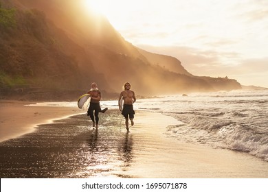 Happy surfers running on beach with surfboards - Sporty friends surfing and training on vacation in tropical coast - People extreme sport lifestyle concept