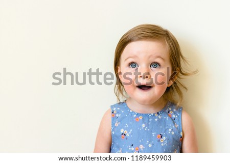 Happy surprised toddler with her mouth open isolated on white. closeup portrait of child girl wearing dress