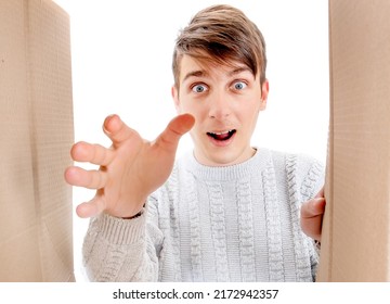 Happy And Surprised Young Man Looking Inside A Box And Reaching A Hand