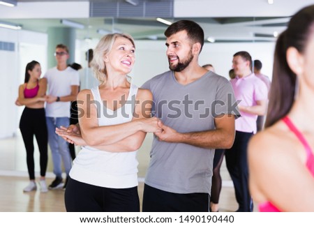   happy swedish men and women  of different ages dancing salsa in dance hall