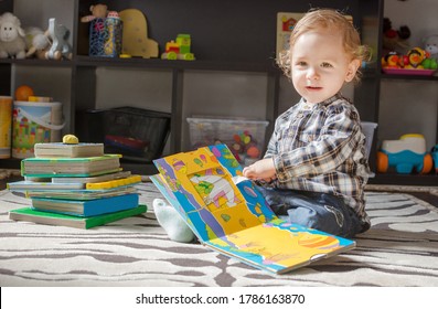 Ein glücklicher, süßer Junge, der Bücher liest, die auf dem Boden sitzen, zu Hause