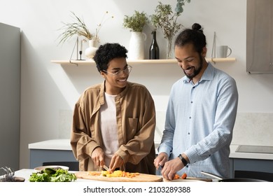 Happy Sweet Dating Black Couple Chopping Fresh Vegetables In Kitchen Together, Preparing Homemade Dinner From Raw Natural Food Ingredients, Talking, Chatting, Laughing, Sharing Household Chores