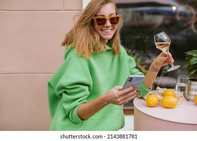 Happy Tanned Woman Drinking Wine And Texting On Phone At Outdoor Cafe. Vacation Mood.