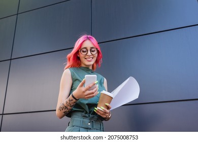 happy and tattooed businesswoman in earphones using smartphone while holding paper cup - Powered by Shutterstock