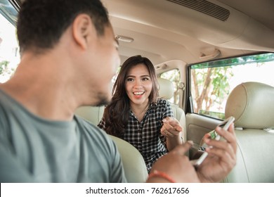 счастливый водитель такси показывает мобильный телефон своему клиенту
