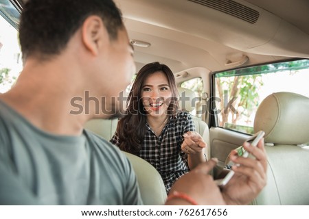 happy taxi driver showing mobile phone to his customer