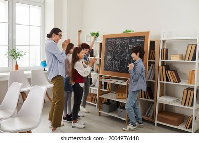 Happy teacher and children playing games and having fun in class. Cheerful school students standing in front of classroom board and applauding classmate for good creative interesting presentation - Powered by Shutterstock