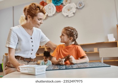 happy teacher encouraging smart girl in Montessori school, learning through play, counting, math - Powered by Shutterstock