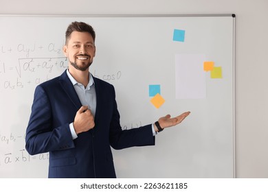 Happy teacher explaining mathematics at whiteboard in classroom - Shutterstock ID 2263621185