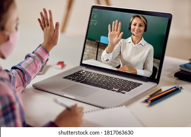 Happy Teacher Greeting Her Student And Waving While Holding Class Over A Laptop During COVID-19 Epidemic. 