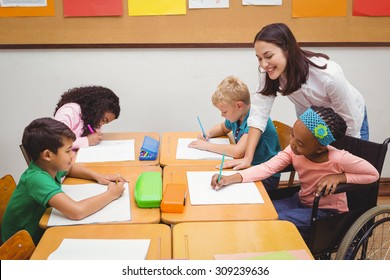 Happy teacher helping her students at the elementary school