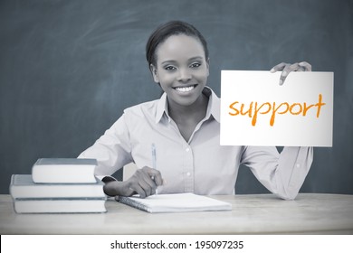 Happy Teacher Holding Page Showing Support In Her Classroom At School