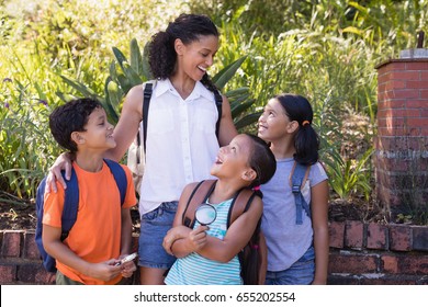 Happy teacher looking at girls standing at nature reserve - Powered by Shutterstock