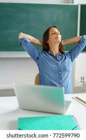 Happy Teacher Taking A Break To Relax And Stretch With Her Arms Behind Her Head And A Blissful Contented Smile