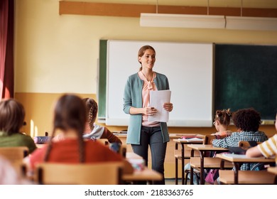 Happy teacher talking to group of kids during a class at school.  - Shutterstock ID 2183363765