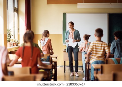 Happy teacher talking to group of kids during a class in the classroom. - Powered by Shutterstock