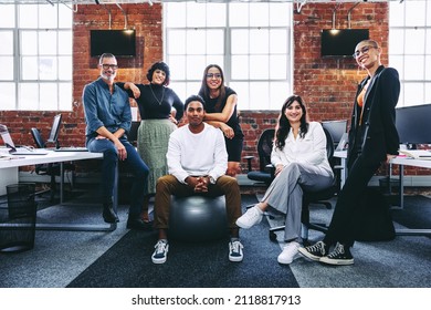Happy team of businesspeople smiling at the camera in a modern office. Business colleagues grouped together in a creative workplace. Diverse team of businesspeople looking cheerful. - Shutterstock ID 2118817913