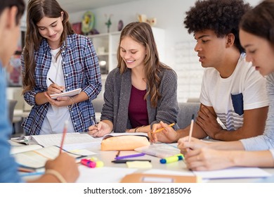 Happy team of high school girls and guys studying together. Group of multiethnic classmates smiling in university library. Group of young people sitting at table working on school assignment. - Powered by Shutterstock