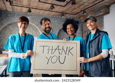 Happy team of volunteers with 'Thank you' placard and donation center looking at camera.  - Powered by Shutterstock