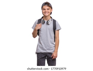 Happy teen boy in cap with headphones and backpack, isolated on white background. Cheerful child smiling and looking at camera. Emotional portrait of handsome teenager guy Back to school.
