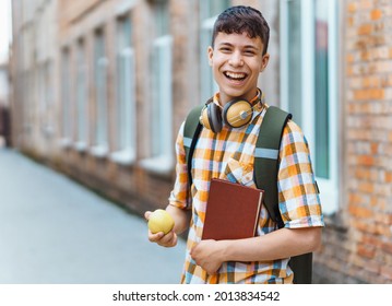 Happy Teen Boy Portrait On The Way To School, He Is Eating An Apple, Education And Back To School Concept