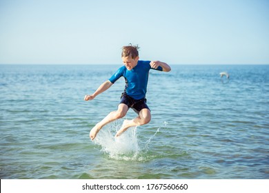 Happy teen child boy playing and jumping in neoprene suit in Baltic sea - Powered by Shutterstock