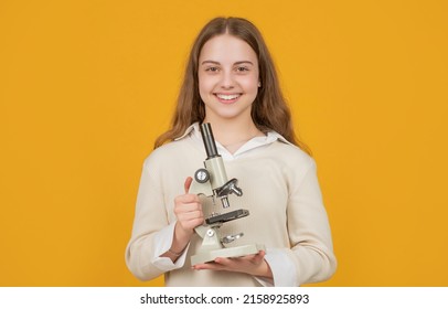 happy teen child with microscope on yellow background