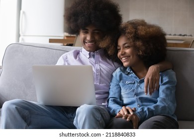 Happy Teen Dating Black Couple Enjoying Leisure Time At Home, Resting On Couch, Watching Funny Movie, Sitcom, Series On Laptop Online, Using Internet Application For Media Files Download