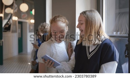 Happy teen friends using mobile phone while standing in school hall. Happy teenage students sharing content on social networks - concept of youth, social. High quality 4k footage