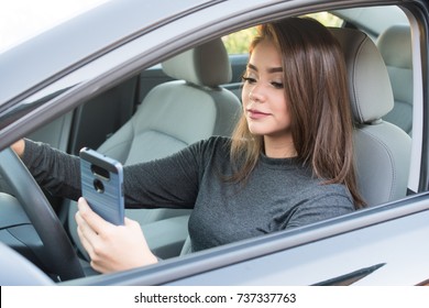 Happy Teen Girl Driving A New Car While Texting