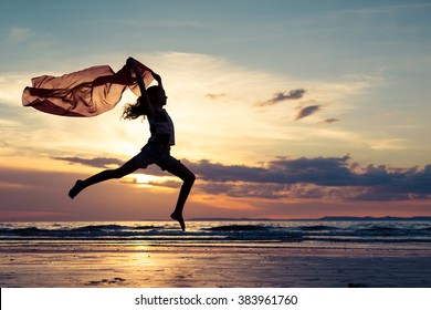 Happy teen girl jumping on the beach at the sunset time - Powered by Shutterstock