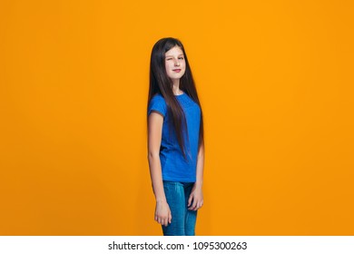 Happy teen girl standing, smiling isolated on trendy orange studio background. Beautiful female half-length portrait. Human emotions, facial expression concept.