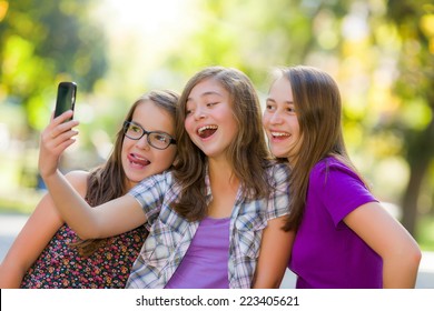 Happy Teen Girls Taking Selfie In Park With Mobile Phone