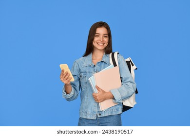 Happy teen Latin girl student holding backpack using mobile phone isolated on blue. Smiling pretty gen z teenager with smartphone in hands wearing denim jacket looking at camera standing on background - Powered by Shutterstock