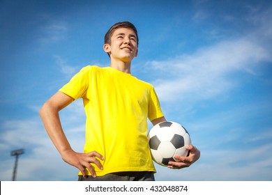 Happy Teenage Boy With A Soccer Ball On A Background Of Blue Sky