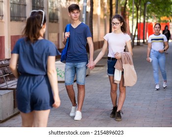 Happy Teenage Couple Holding Hands Strolling Together Along City Street On Summer Day. Teen Romance Concept