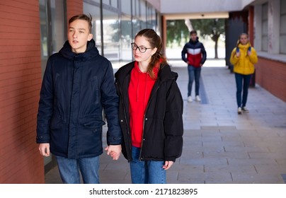 Happy Teenage Couple Holding Hands Walking Together To College Campus On Spring Day. Teen Romance Concept