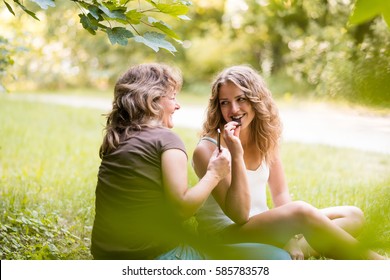 Happy Teenage Daughter With Mother Eating Chocolate Bar