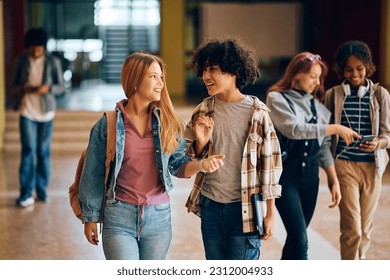 Happy teenage girl and her African American friend communicating while going on a class at high school. - Powered by Shutterstock