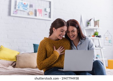 happy teenage girl and mother watching comedy movie on laptop in bedroom - Shutterstock ID 1947794938