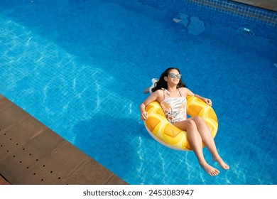 Happy teenage girl relaxing in inflatable ring in swimming pool, view from above - Powered by Shutterstock