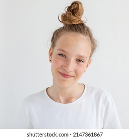 Happy Teenage Girl In White Shirt On A Wall Background. A Smiling 12 Year Old Teenager With Long Curly Hair. Schoolgirl