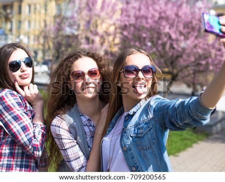 Happy teenage girls doing selfie, hawing fun spend time together in the city park
