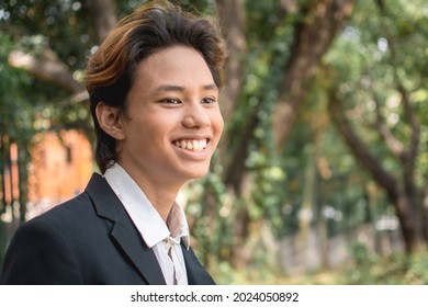 A happy teenage man of Filipino or Pacific Islander descent. In formal wear or university uniform. Candid shot.