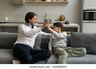 Happy Teenage Son Boy Giving High Five To Cool Dad. Loving Father Spending Leisure Time With Teen Child, Talking, Chatting, Expressing Support, Praise, Pride, Approval, Celebrating Kids Success