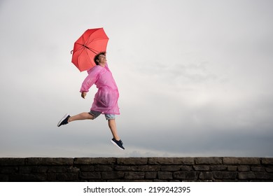 Happy Teenager Boy Jumping And Dancing In The Rain. Bad Weather And Positivity Concept.