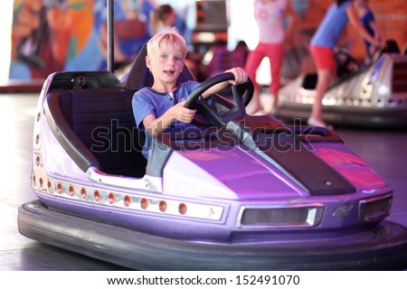 Happy teenager boy rides electric car during fan-fair entertainment