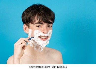 Happy Teenager Boy Shaving Face With Foam And Razor.